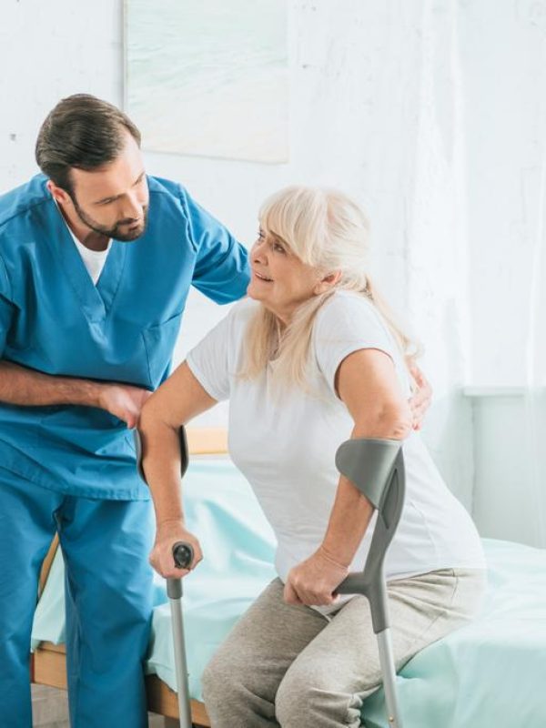 stock-photo-male-social-worker-helping-sick-senior-woman-crutches