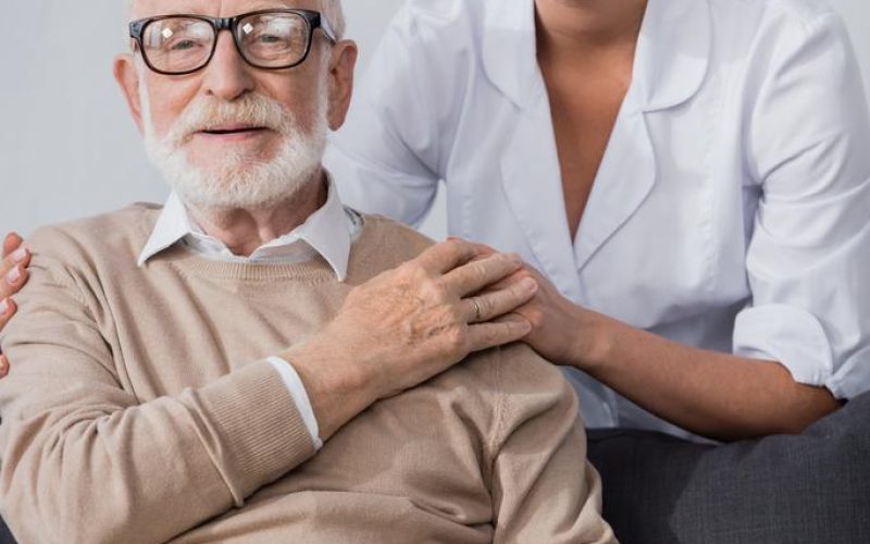 stock-photo-social-worker-holding-hands-embracing-aged-man-while-looking-camera